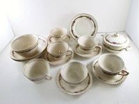 Full set of 11 pieces arranged on white surface showing cups, saucers, bowls, plate and sugar bowl with lid.