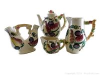 Four-piece ceramic set including teapot, pitcher, double cruet, and creamer with colorful fruit motifs and bamboo style handles.