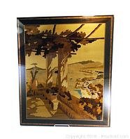 Front view of wooden inlay wall art featuring an outdoor veranda scene with columns and distant hills, framed and protected by glass.
