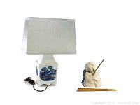 Photo of the vintage Chinese lamp with blue scenic design base, white rectangular fabric lamp shade, and vintage cherub incense holder next to a pencil for scale.