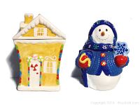 Front view of the yellow gingerbread house cookie jar next to the Bico snowman cookie jar, highlighting their design and size.
