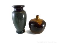 Two glazed pottery vases, tall black and shorter brown, shown from a frontal angle to highlight shape and color.