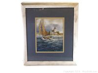 Frontal view of the matted and framed nautical watercolor art print signed by Ian Ramsay showing a sailboat with a lighthouse background.