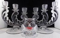 Two vintage crystal 3-candle slot candlestick operas and a glass owl tea-light holder placed in front on black background