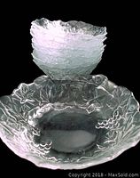 Stack of six clear glass bowls showing grapevine pattern with grape clusters, vines, and leaves around the rim.