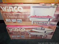 Two WinCo stainless steel chafing dishes in original boxes stacked on top of each other on carpeted floor. The boxes show product info and food images.