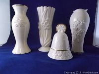 Full view of the set of four Lenox fine china pieces: three vases with floral embossing and gold holiday trim, and one bell.