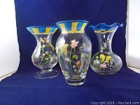 Three hand-painted Lenox Butterfly Meadow glass vases with floral and butterfly designs and distinctive blue and yellow rims.