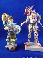 Two vintage clown figurines standing side by side with blue background showing size comparison and details
