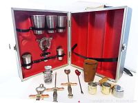 Open metallic case displaying red interior and multiple metal bar tools held by elastic straps and placed outside the case