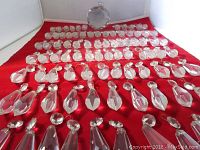 All 89 small and medium-sized chandelier prism crystals arranged on red fabric with large crystal ball positioned near top center.