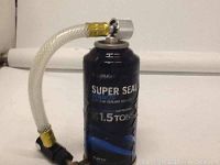Black canister labeled 'Super Seal Advanced Leak Sealer' with a connected flexible hose and metallic valve fitting shown upright.