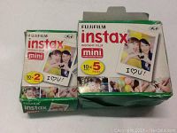 Photo shows two Fujifilm Instax Mini instant film packs: a 2-pack and a 5-pack, totaling 7 packs of instant film.