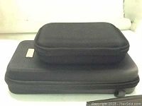 Photo shows two black reinforced carrying cases stacked; one medium and one larger size, both rectangular with zipper closures.