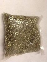 Clear plastic bag filled with about 1000 small gold-toned metal washers, visible circular shape and central holes.