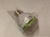 LED shower head in packaging, showing connected brass threaded fitting and white plastic body with green ring detail.