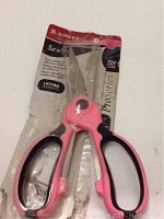 Singer Sew Pro 8-inch scissors with pink and black ergonomic handles shown in original packaging with product branding and lifetime guarantee visible.