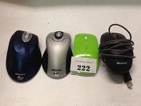 Four Microsoft computer mice in various colors and connectivity types arranged side by side: black wired mouse, silver wireless mouse, green wireless mouse, black wireless mouse.