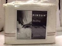 Photo of the Pinzon Bedding sheet set in clear sealed plastic packaging with label showing brand and product details