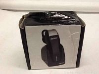 Photo shows the Shark Bluetooth headset packaging box. The box features an image of the black wireless Bluetooth headset seated in its charging dock. The box appears slightly worn with creases and minor damage.