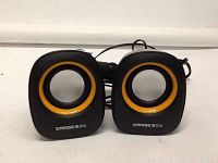 Photo showing two compact Carise computer speakers with orange accented drivers connected by wires.