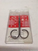 Top-down photo showing Rubis Switzerland nail and cuticle scissors sealed in clear plastic clamshell packaging with red and white Swiss cross branding and contact information visible.