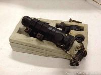 Photo of the black Firefield rifle laser sight with attached coiled wire remote switch on white foam packaging.