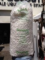 Full view of large clear plastic bag filled with white packing peanuts showing the brand name 'Renature' printed in green.