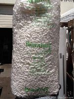 Full view of a large transparent bag filled with white packing peanuts. The bag shows the brand Renature and some printed usage instructions.