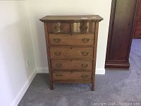 Front view of refurbished antique wooden dresser showing 5 drawers with brass handles and some wear on wood.