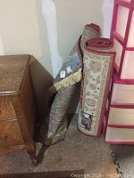 Two rolled area rugs leaning against a wall showing the general condition and patterns near edges.