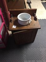 Wooden chamber pot cabinet with closed door and ceramic pot on top