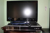 Front view of Emerson 26 inch LCD TV sitting on RCA DVD player with HDMI cable placed on top. TV screen is black with Emerson branding below.
