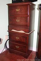 Photo showing one stacked night table revealing the full height and drawer handles with visible wear and scratches