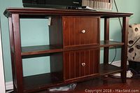 Front view of wooden TV stand with hinged doors and open shelves, showing overall design and condition.