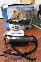 Photo of boxed Intex full size inflatable air mattress and Ozark Trail dual action hand pump with hoses and multiple attachment nozzles.