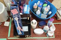 Photo showing all items together including personal care bottles, cold ice pack, boxed wall grab bar, Quo beauty case and other items on a table