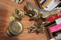 Photo showing all four brass pieces on wooden surface, including eagle, elephant, and two candle holders