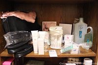 Full view of cosmetic bags, storage containers, purse, various boxed and bottled skincare products arranged on shelf.
