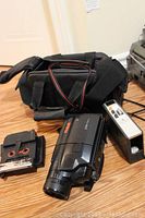 RCA PROV730 camcorder with carrying case, instruction manual, and tapes on hardwood floor
