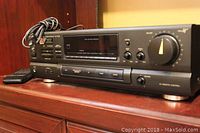 Side view of the Technics SA-GX190 AV control stereo receiver with remote placed beside it on a wooden surface.