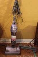 Full upright view of the Shark Vac and Steam corded vacuum steam mop in light purple, showing handle with wrapped cord and main body with control buttons.