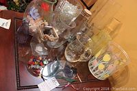 Overview of various glass vases, painted glass pieces, and a plastic ice bucket with tulip designs on a reflective surface.