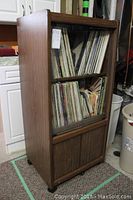 Wooden storage cabinet filled with vinyl albums and records, showing overall cabinet and storage capacity.