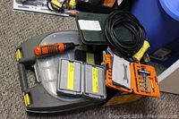 Seven inch portable cut off saw, Black and Decker cordless drill, orange bit cases, power cord coiled on carpet.