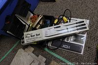 Full view of pry bar set box, screwdriver set pouch, jig saw and blade cases laid on carpet.