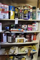 Metal shelving unit with multiple shelves, holding painting supplies and chemicals as described.