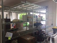 Full view of three section chrome plated wire shelving unit with various objects on shelves