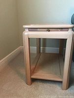 Front view of one Hammary oak end table showing drawer and lower shelf under natural light.