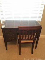 Full view of wooden sewing cabinet and chair in front of a window showing design and dimensions.